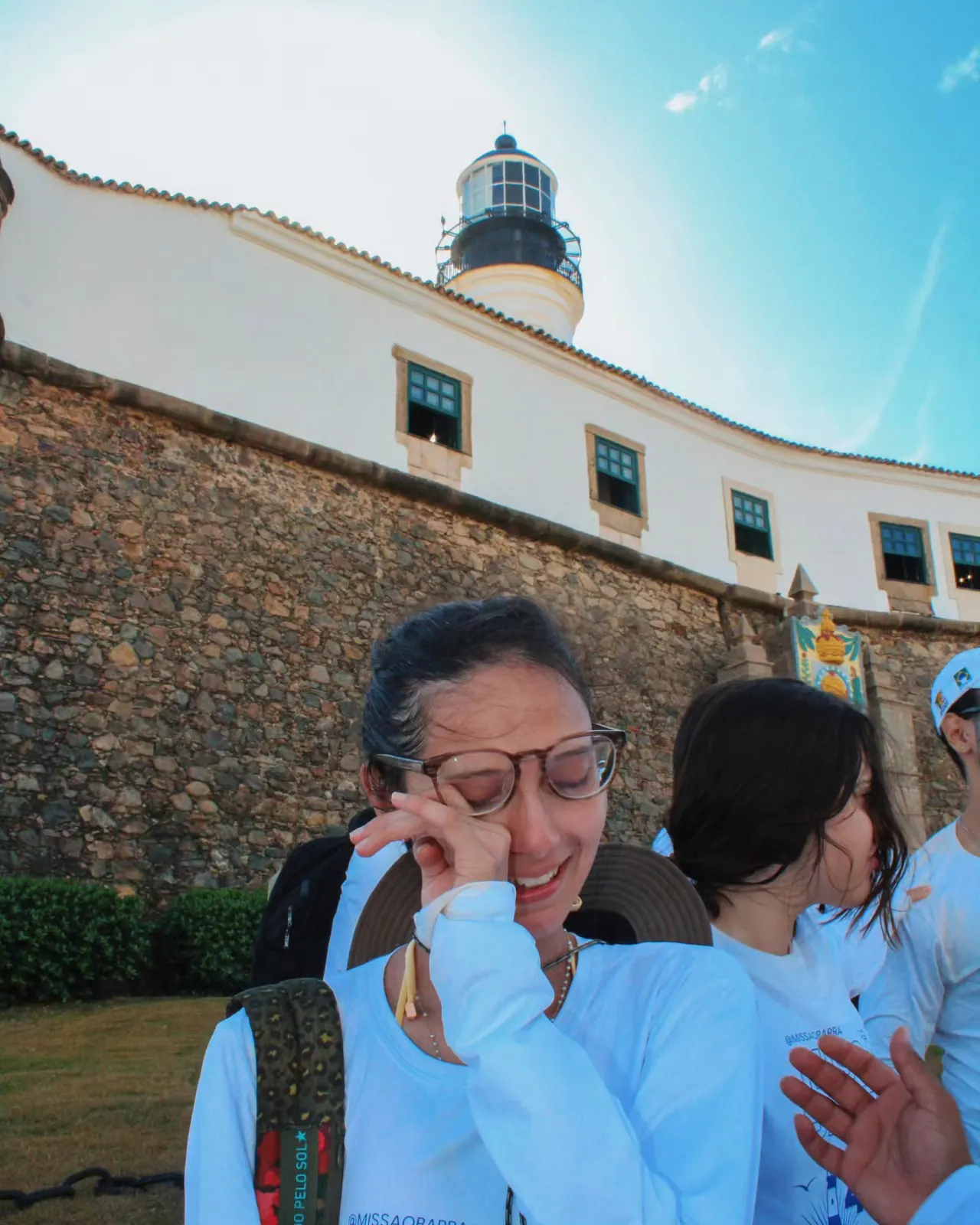Participante emocionada enxugando as lágrimas na chegada, em frente ao Farol da Barra