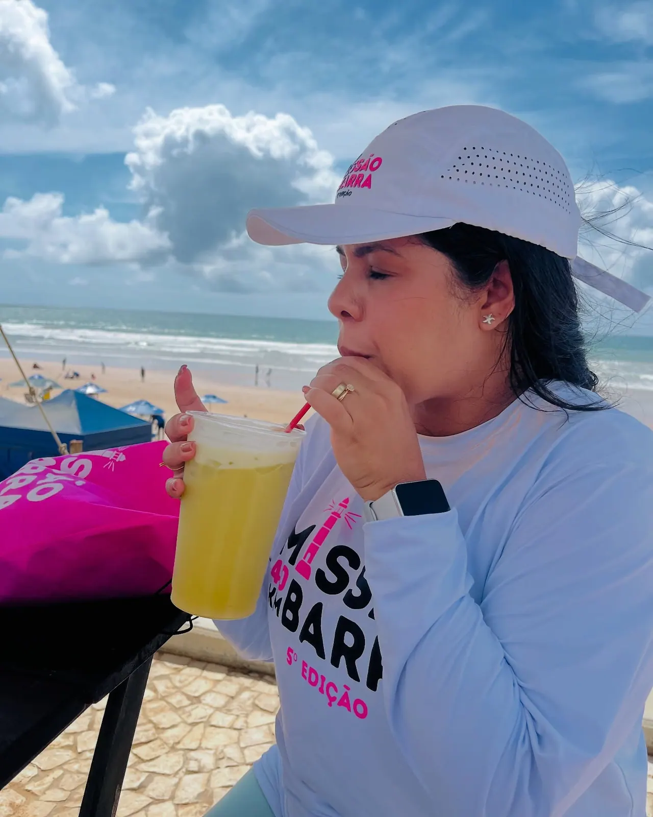 Participante da 5ª edição se hidratando com um copo de suco na orla